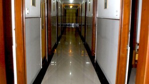 A long, narrow hallway with wooden doors on either side and a shiny tiled floor. - Hotel Gangasagar (Bengaluru)