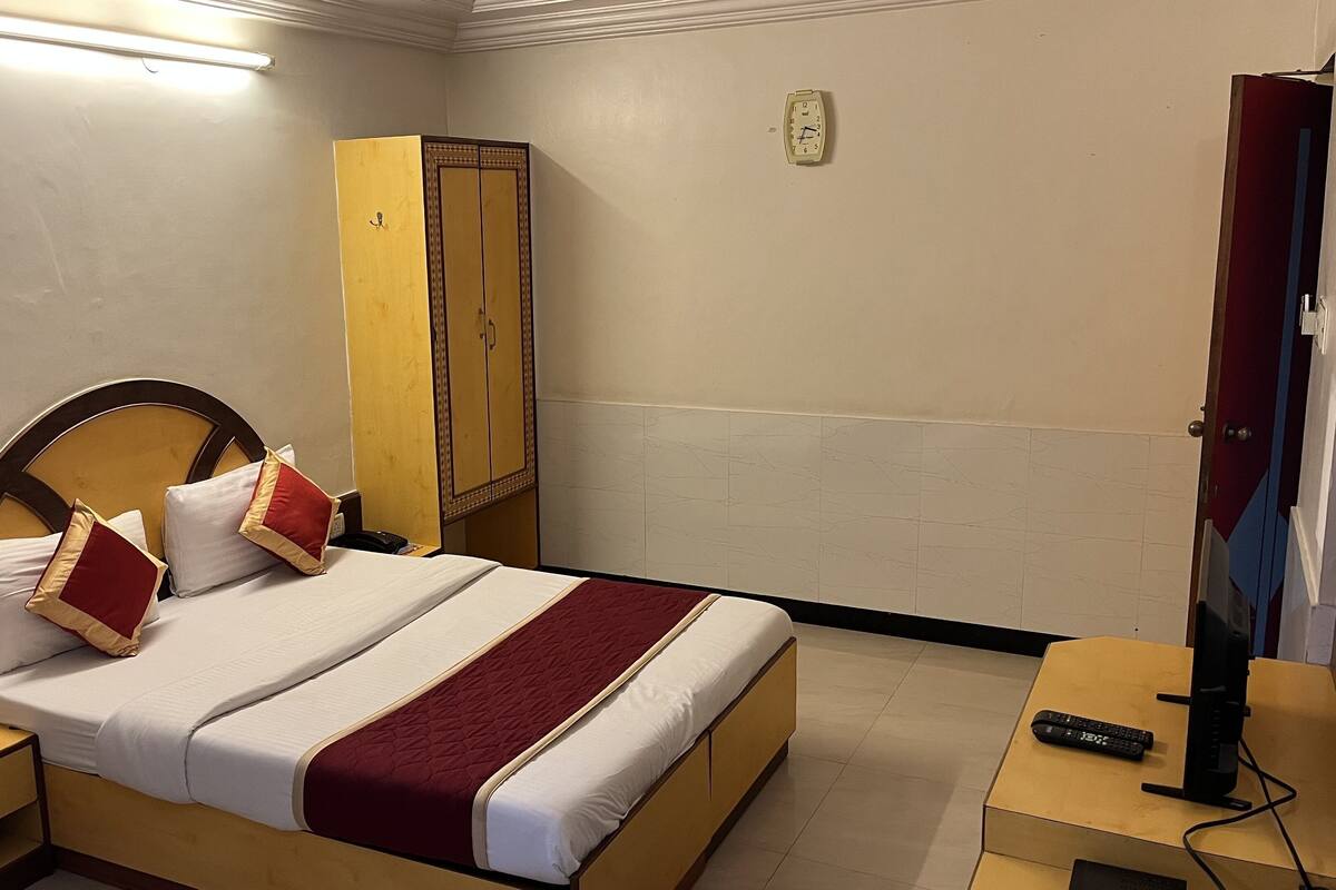 Habitació d'hotel amb llit, armari, televisió i una taula de nit.