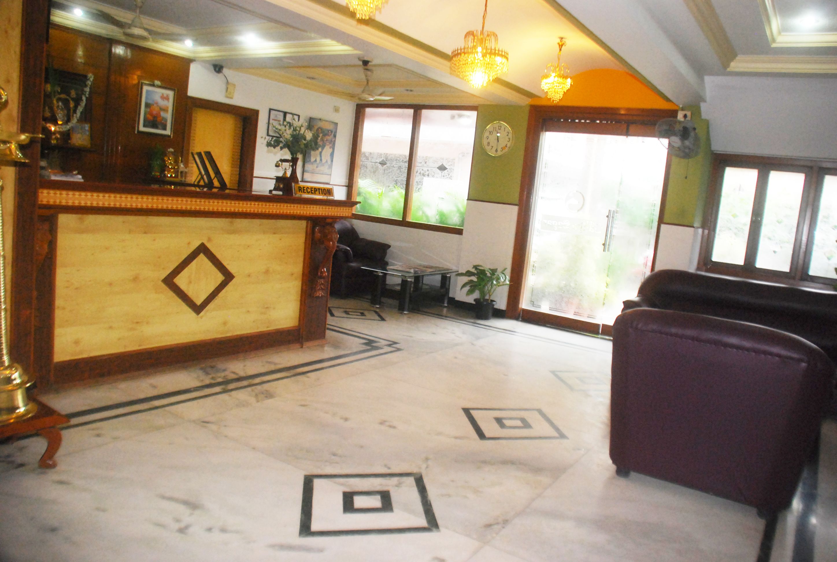 A reception area with a marble floor, a reception desk, a clock, and a window with a view.