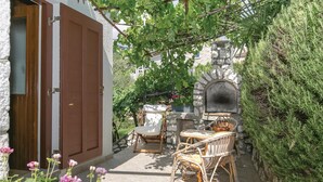 A courtyard with a stone oven, wicker furniture, and a door with a metal handle. - 1 bedroom lovely home in Zagorje (Zagorje)