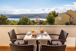 Une table à manger entourée de chaises en osier, recouverte d’une nappe blanche, et offrant une vue magnifique sur un lac et des montagnes en arrière-plan.