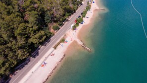 An aerial view of a coastal road with a beach on one side.