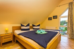 Une chambre à coucher avec un lit, une table de chevet, une lampe et une fenêtre avec des rideaux.
