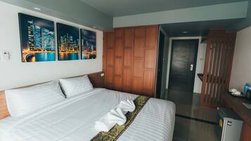 A hotel room with a large bed, wooden wardrobe, and a cityscape view.