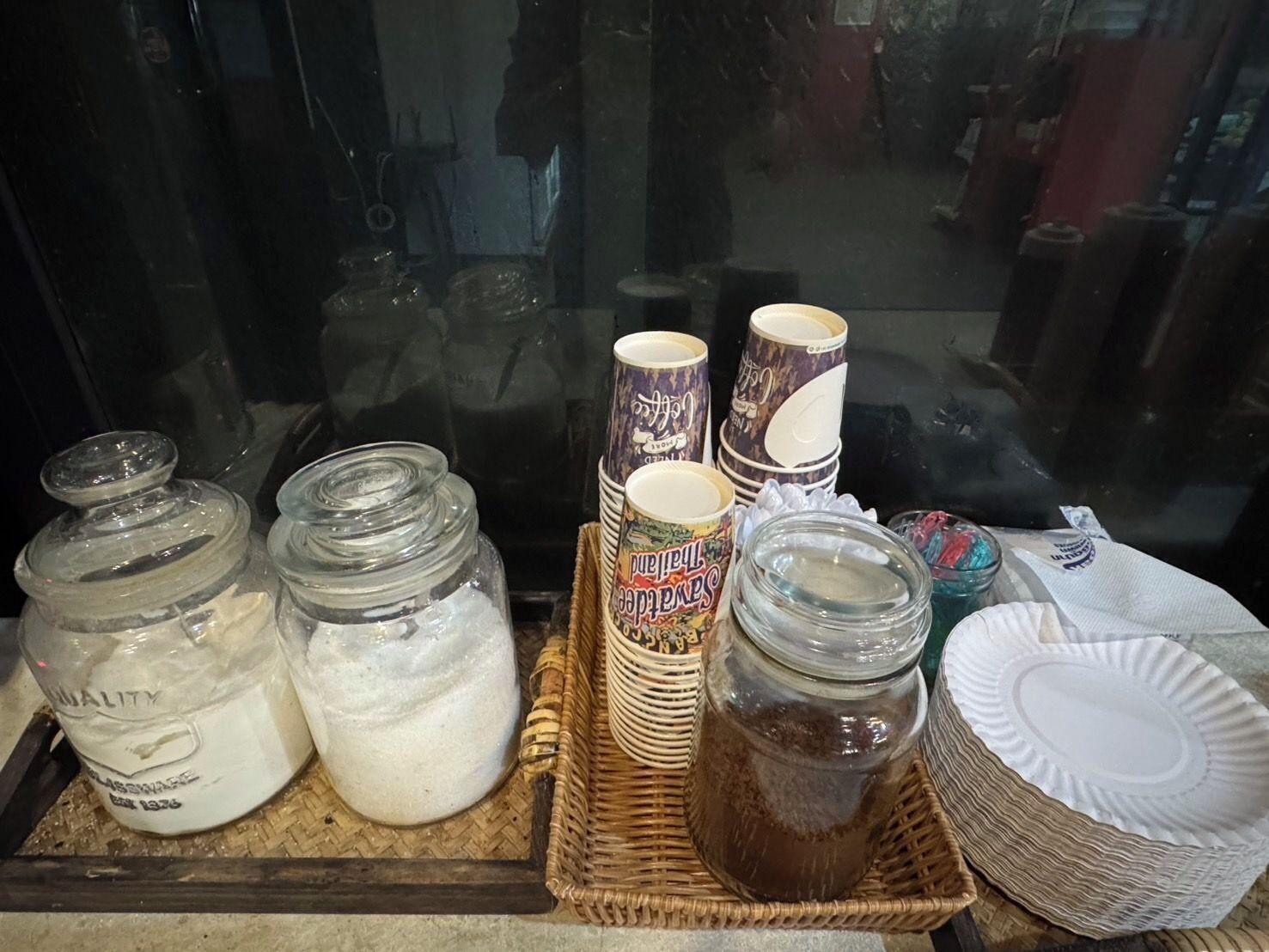 A display of glass jars with lids, stacked paper plates, and a wicker basket.