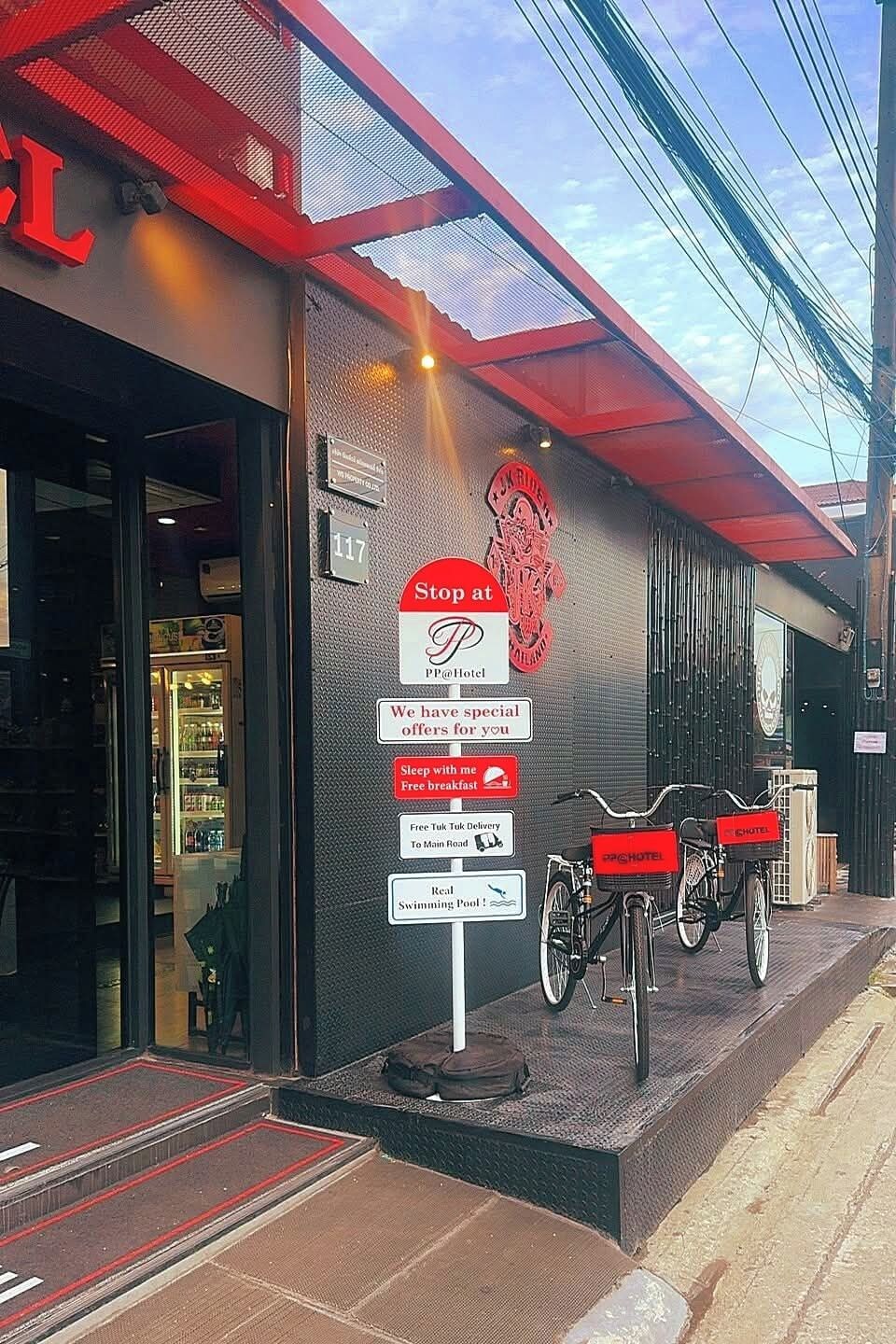 A hotel entrance with a sign advertising special offers, a bike rental service, and a swimming pool.