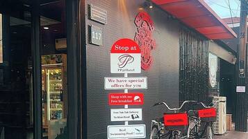 A hotel entrance with a sign advertising special offers, a bike rental service, and a swimming pool.