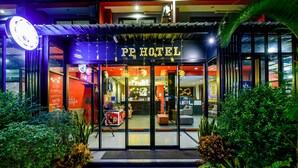 L’entrée d’un hôtel, avec une enseigne indiquant « PE HOTEL », et un café à l’intérieur.