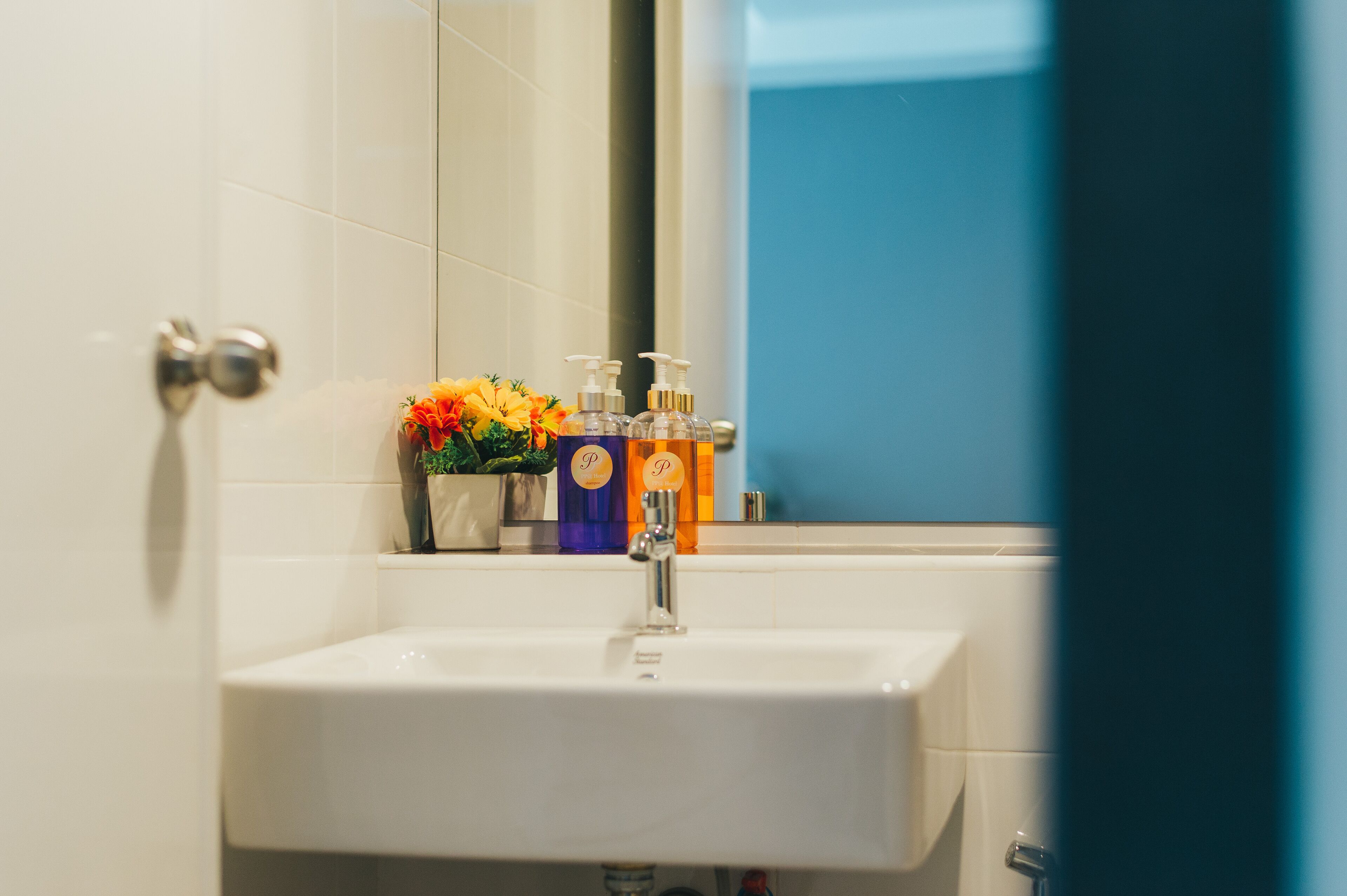 A bathroom with a white sink, a mirror, and toiletries on the counter.