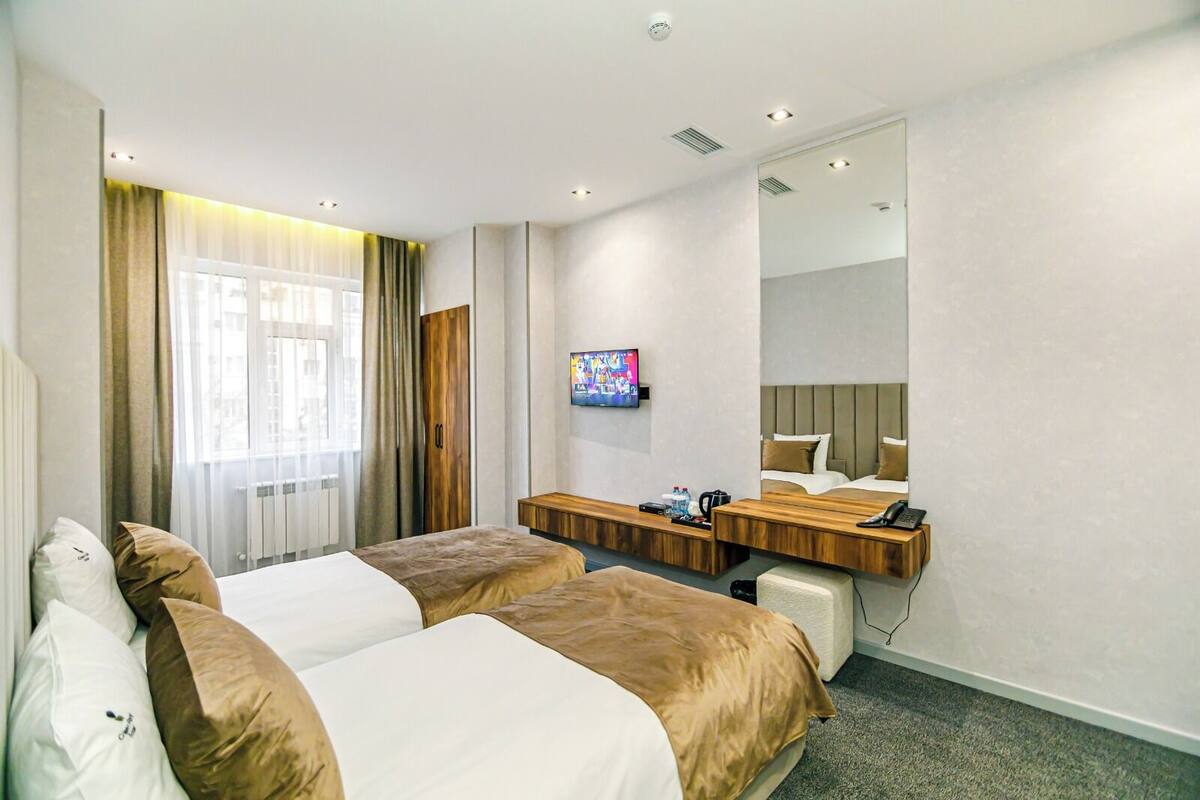 Habitació d'hotel amb dos llits, televisió, escriptori i mirall.