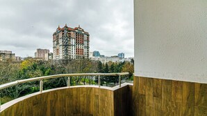 Un balcón con barandilla de madera curvada que da a una vista de la ciudad con edificios modernos.