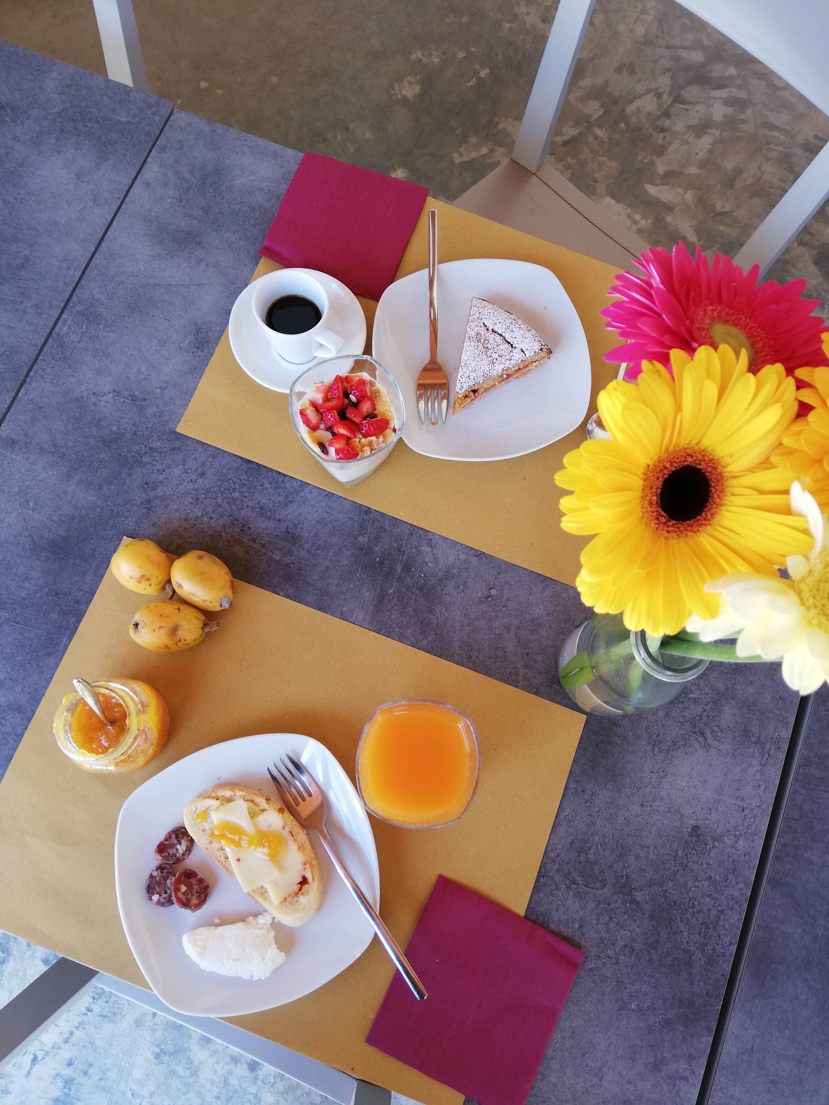 A table with a variety of breakfast items including toast, jam, and a glass of orange juice.