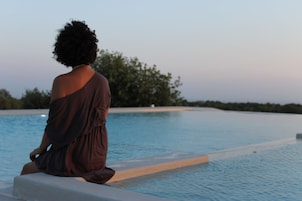 Una persona seduta a bordo piscina con vista sull'orizzonte.