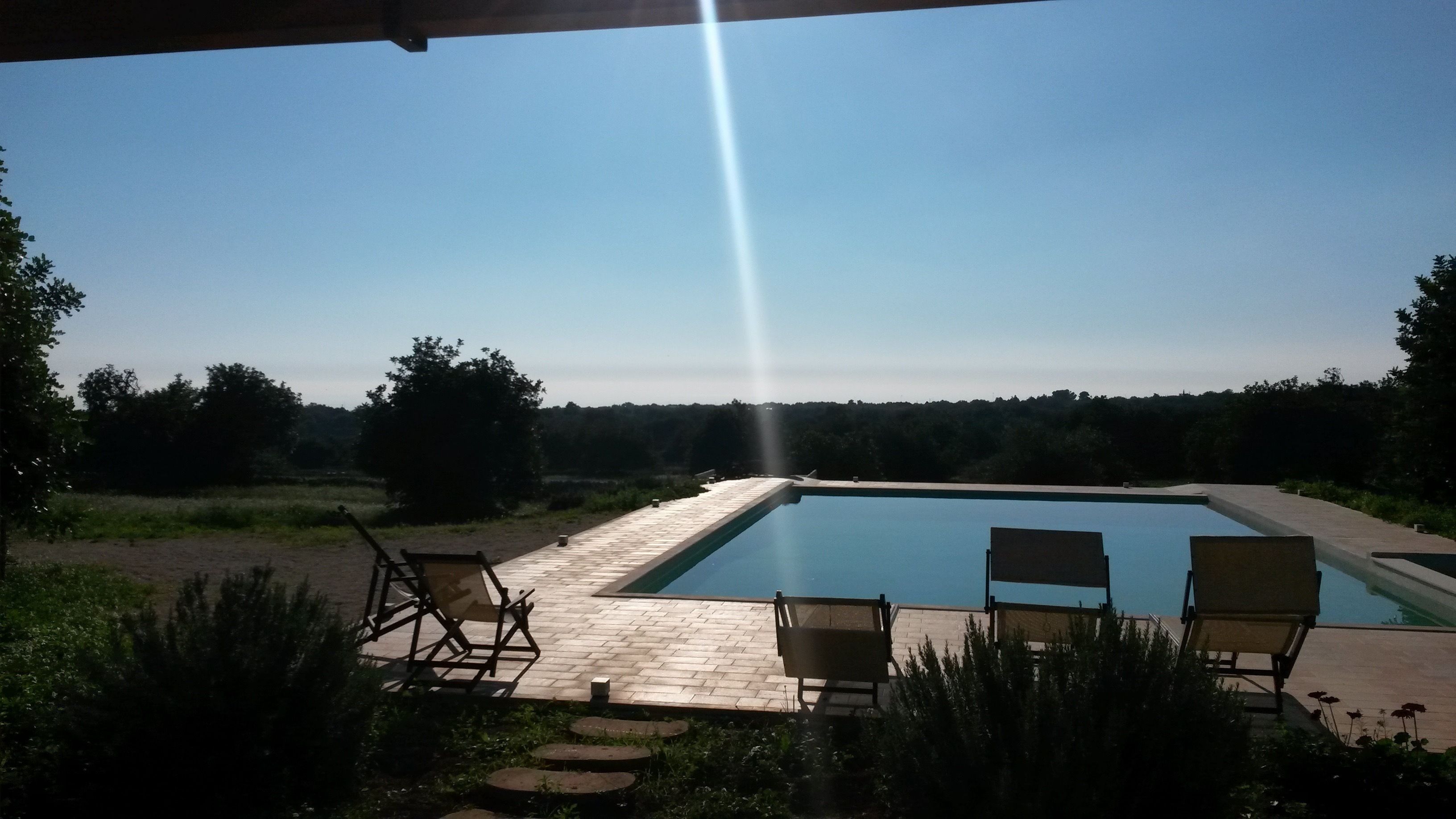 Ein Swimmingpool mit zwei Liegestühlen und einer Betonplattform.
