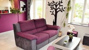 A modern living room with a purple sofa, a coffee table, and a dining area. - House in Touraine with Spa and Sauna, near Loire Castles (Benais)