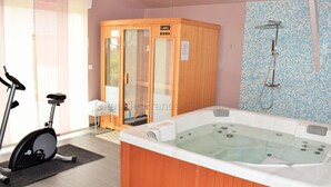 A modern bathroom with a wooden sauna, a large bathtub, and a shower area. - House in Touraine with Spa and Sauna, near Loire Castles (Benais)