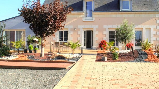 A two-story house with a tiled driveway, a small garden with various plants, and a visible door. - House in Touraine with Spa and Sauna, near Loire Castles (Benais)