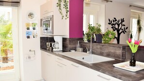 A modern kitchen with a large island, a built-in oven, and a sink. There are plants and a vase with flowers on the counter. - House in Touraine with Spa and Sauna, near Loire Castles (Benais)