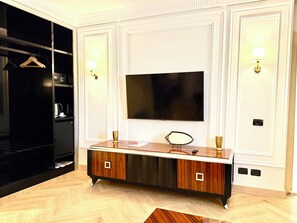 A modern living room with a flat-screen TV mounted on the wall, a black entertainment unit, and a wooden cabinet with a mirror.