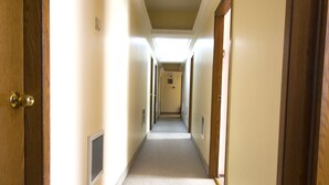 A long, narrow hallway with wooden doors on both sides, leading to a bright room at the end. - Acikgoz Hotel (Edirne)