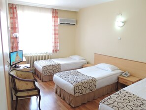 Una habitación de hotel con dos camas, una silla, un televisor y una mesita de noche con un teléfono.