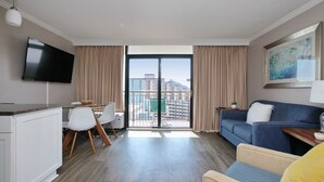 Une chambre d’hôtel moderne dotée d’un balcon, d’une télévision à écran plat, d’un coin repas et d’un canapé.