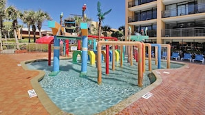 Un espace de jeux aquatiques avec des structures colorées et des palmiers en arrière-plan.