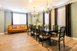 A dining area with a wooden table and chairs, a sofa, and a chandelier. - New Built, Backyard & Balcony Fireworks, Walk To Disney, 4000 sqft, No Pool Fee (Anaheim)