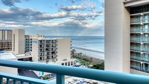 A high-rise hotel with multiple balconies overlooking a beach and ocean.