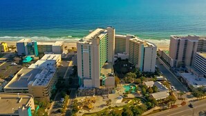 A coastal hotel with multiple buildings, a parking area, and a pool. - 3Bd Condo in Beachside Resort w/ Amenities Galore! (Myrtle Beach)