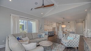 A spacious living area with a large sofa, a round coffee table, and a dining area with a chandelier.