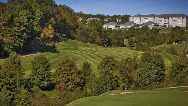 A golf course with a clubhouse and residential buildings in the background. - A grand vacation is guaranteed when you rent this HUGE 4 bedroom condo! (Branson)