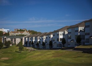 Una hilera de edificios de apartamentos blancos con un área verde al frente.