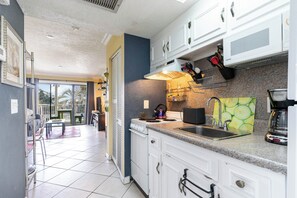 A kitchen with white cabinets, a granite countertop, a stove, and a sink.