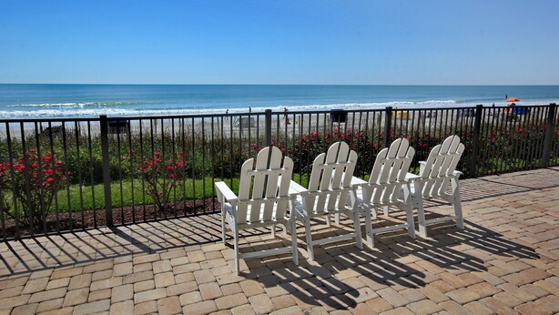 A patio with Adirondack chairs overlooking a beach.