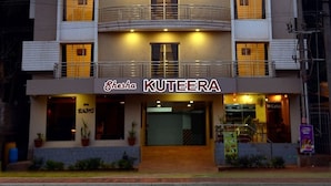 Un immeuble à plusieurs étages doté de balcons, une enseigne indiquant « KUTEERA » et une devanture portant l’inscription « Cafétéria ».