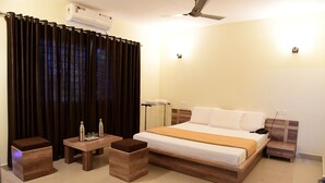 Une chambre d’hôtel moderne avec un grand lit, des meubles en bois, un ventilateur de plafond et un appareil de climatisation.