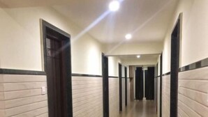 Un long couloir étroit, doté d’un plancher en bois et de murs blancs agrémentés de moulures noires.