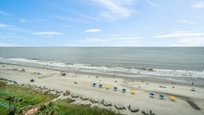 A beach with rows of umbrellas and beach chairs, a clear sky, and the ocean. - Direct Oceanfront Studio On The Golden Mile (Myrtle Beach)
