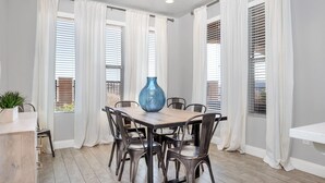 A dining area with a wooden table and metal chairs, white curtains, and a blue vase. - The Florentine - Pool! Hot Tub! (Washington)