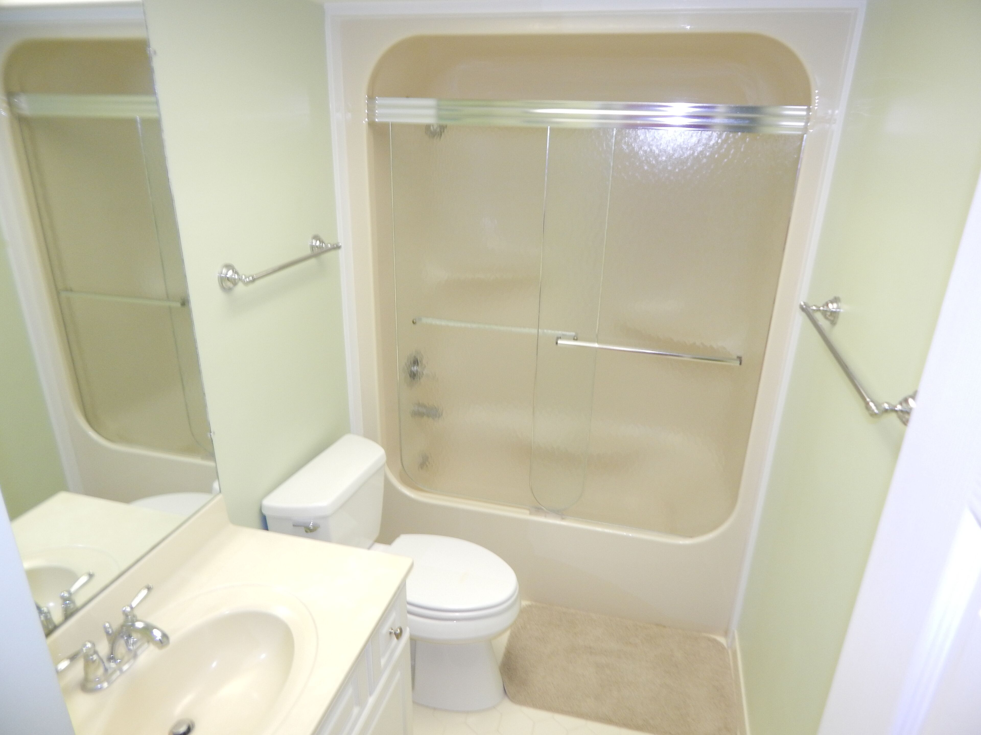 A bathroom with a bathtub, toilet, sink, and a mirror.