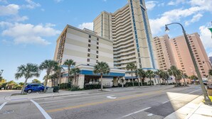 A multi-story hotel with a modern design, featuring a prominent corner building and several palm trees in front. - Amazing Views 30 ft. balcony 1 bedroom Myrtle Beach (Myrtle Beach)