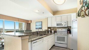 A modern kitchen with white cabinets, a granite countertop, a built-in microwave, and an oven. - Amazing Views 30 ft. balcony 1 bedroom Myrtle Beach (Myrtle Beach)