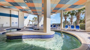 A pool area with a tiled edge, lounge chairs, and palm trees. - Amazing Views 30 ft. balcony 1 bedroom Myrtle Beach (Myrtle Beach)