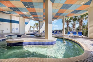 Un espace piscine avec une bordure carrelée, des chaises longues et des palmiers.