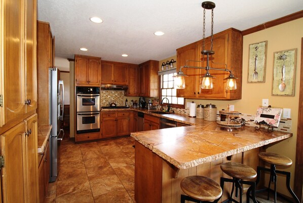 A kitchen with wooden cabinets, stainless steel appliances, and a central island with stools.