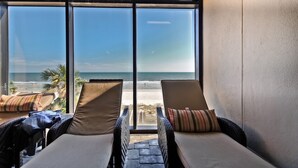 A room with two reclining chairs facing a large window overlooking a beach. - Oceanfront Condo on The Golden Mile in Myrtle Beach (Myrtle Beach)
