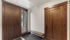 A hallway with wooden doors, a bench, and a door mat. - Spacious Mountain Home, Panoramic View from Private Balcony, Central Location (Silverthorne)