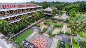 A hotel with a large outdoor pool area, multiple levels of balconies, and lush greenery surrounding the property. - Pancur Gading Hotel & Resort (Petumbak)