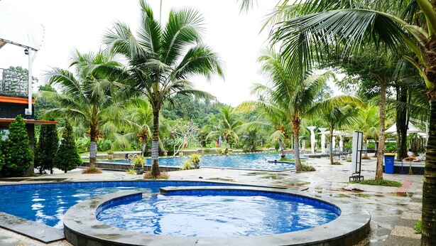 A pool area with multiple water features, surrounded by palm trees and greenery. - Pancur Gading Hotel & Resort (Petumbak)